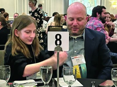 New York publisher Brett Freeman and his daughter compete with friends around the table in a game of “Pass the dice” at the 2023 NYPA convention.