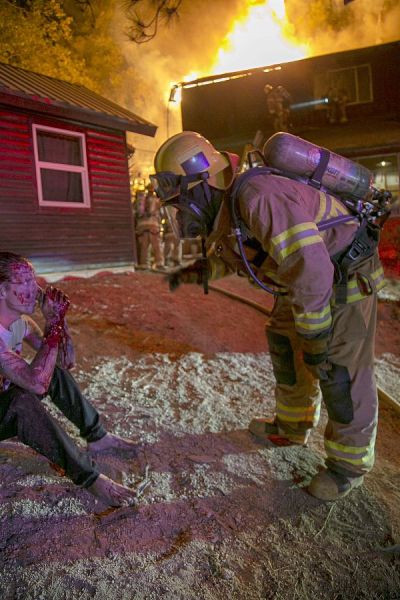 A firefighter checks on the well-being of the male victim as the fire rages on. (Jenny Kirchner | Idyllwild (California) Town Crier)